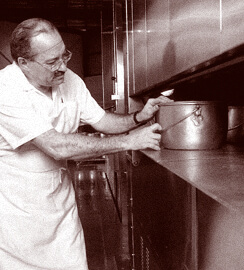 Cook putting a pot of beans with pork in the oven