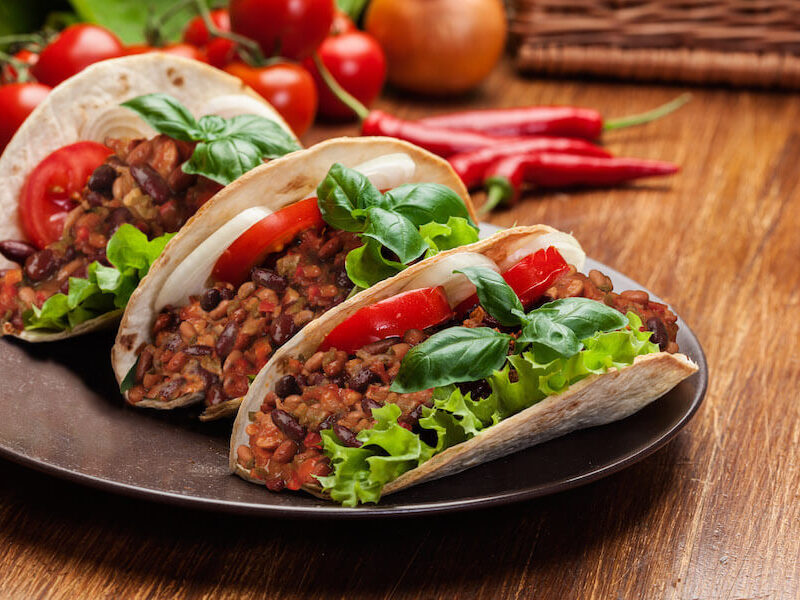 Vegetable chili tacos garnished with tomatoes, lettuce, onions and fresh basil